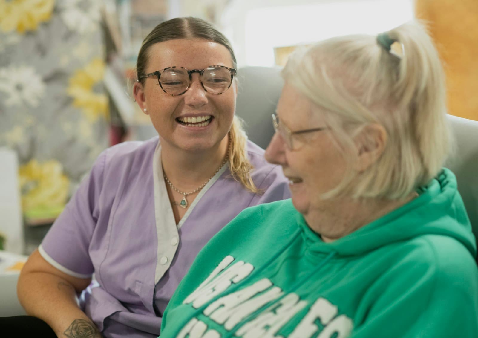 A support worker and an older woman laughing together, representing the community organisations the Henry Smith Charity funds