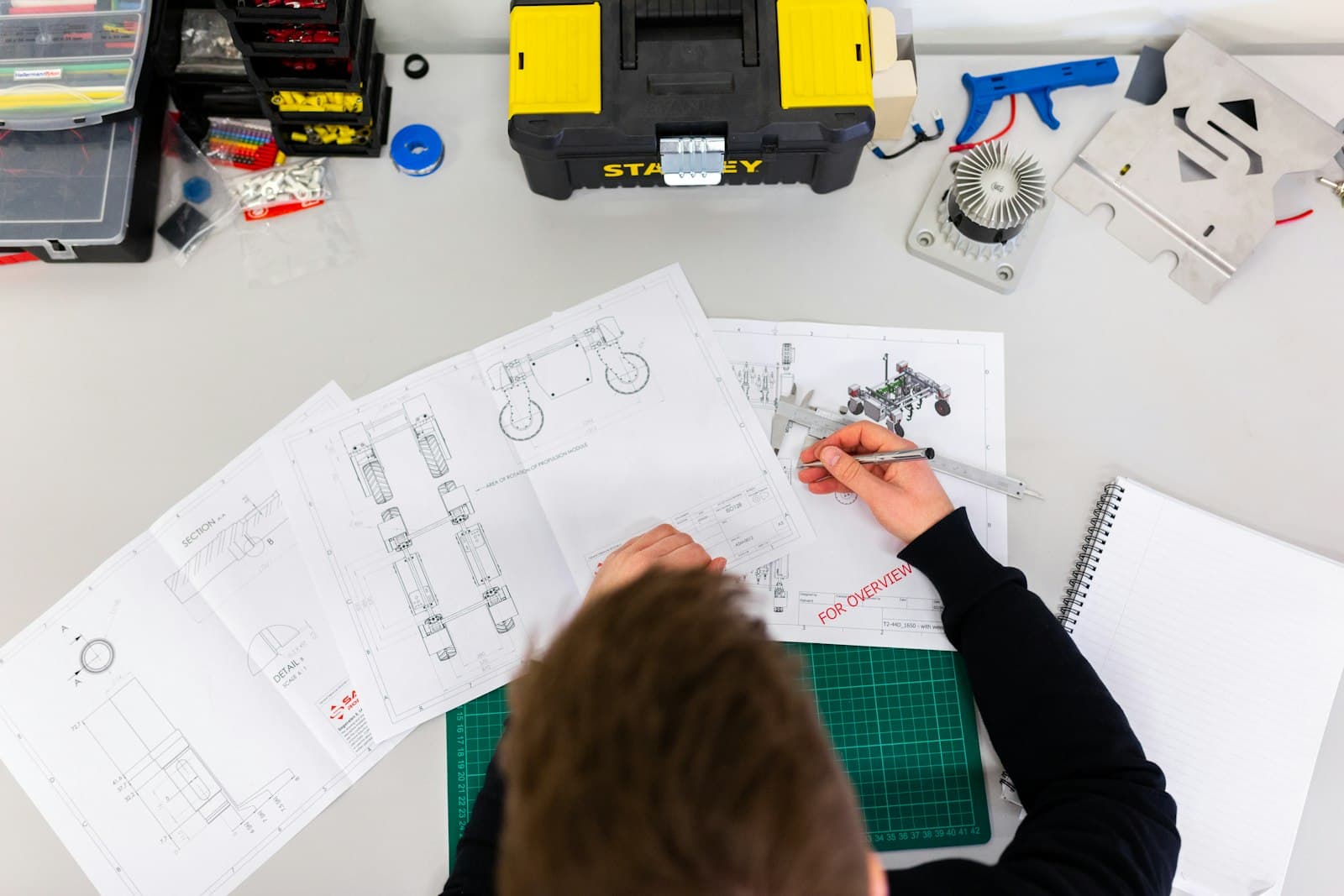 An engineer using a caliper over technical drawings, representing the technical uncertainty innovation grants fund